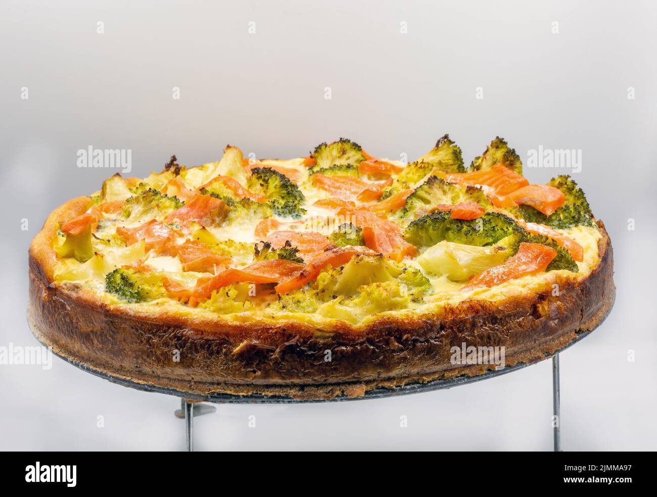 Open pie with salmon and broccoli closeup. Homemade quiche. Stock Photo
