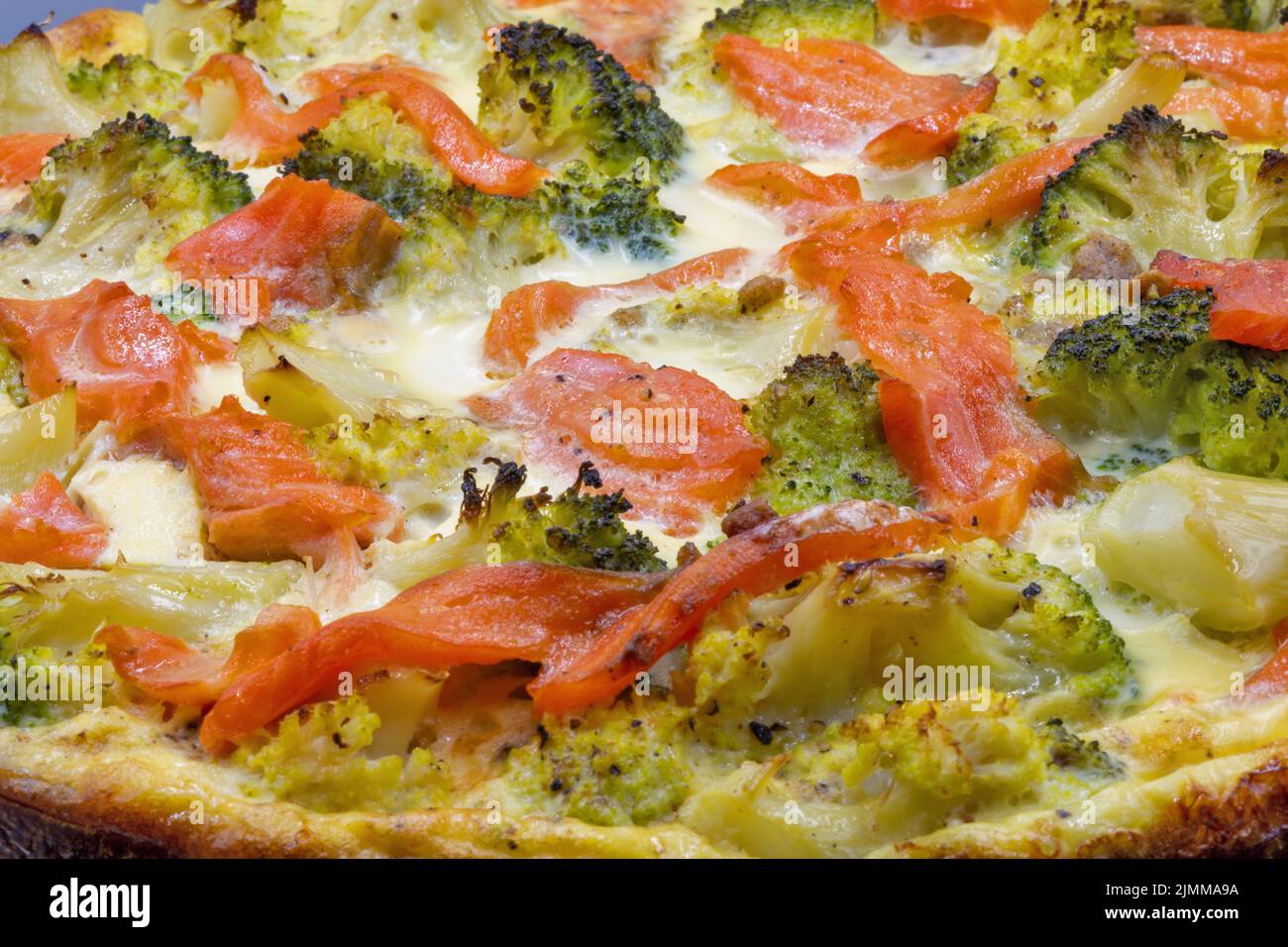 Open pie with salmon and broccoli closeup. Homemade quiche. Stock Photo