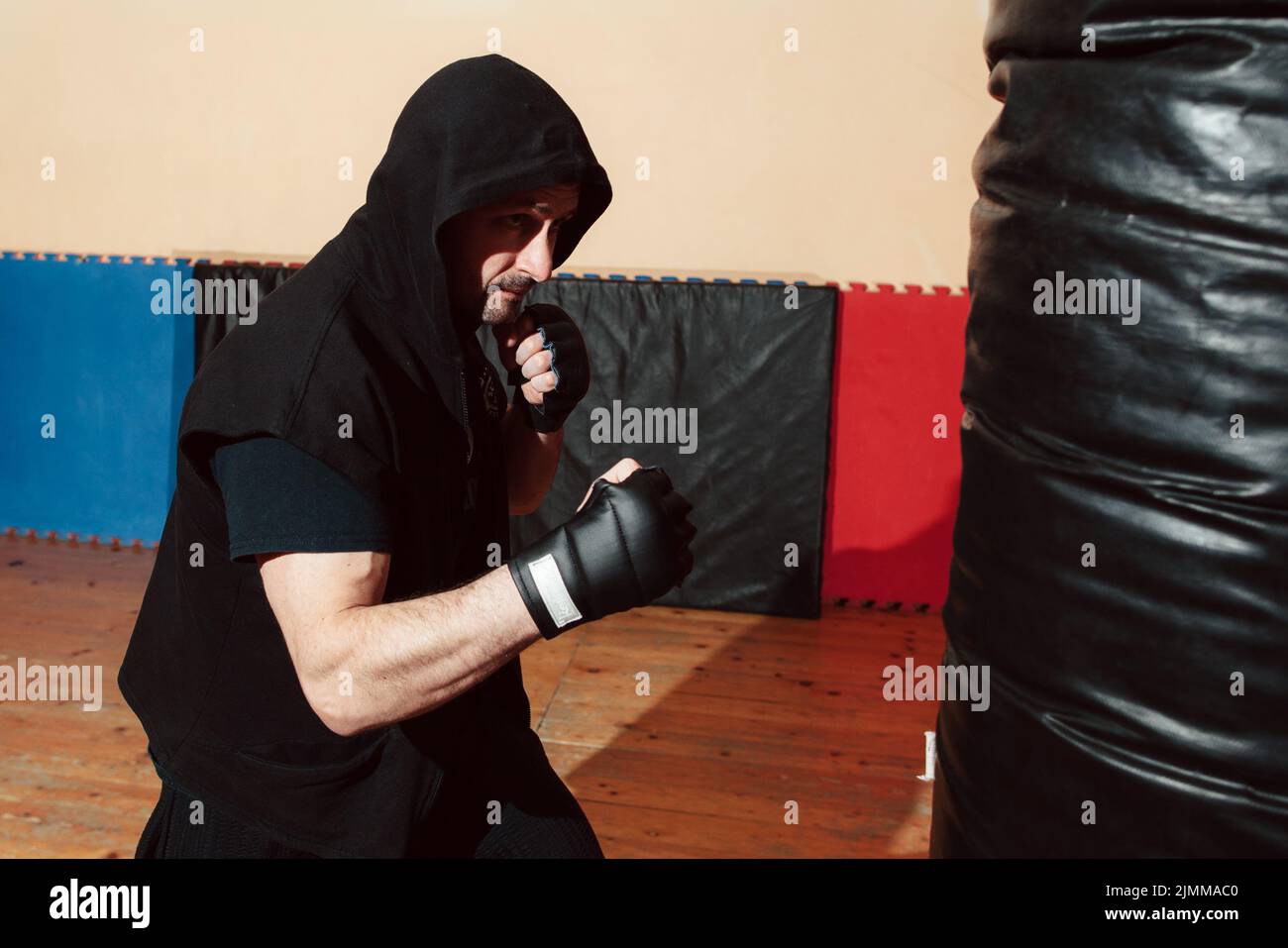 Man training with punching bag at gym Stock Photo