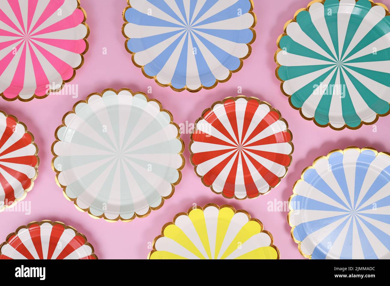 Colorful striped paper party plates on pink background Stock Photo
