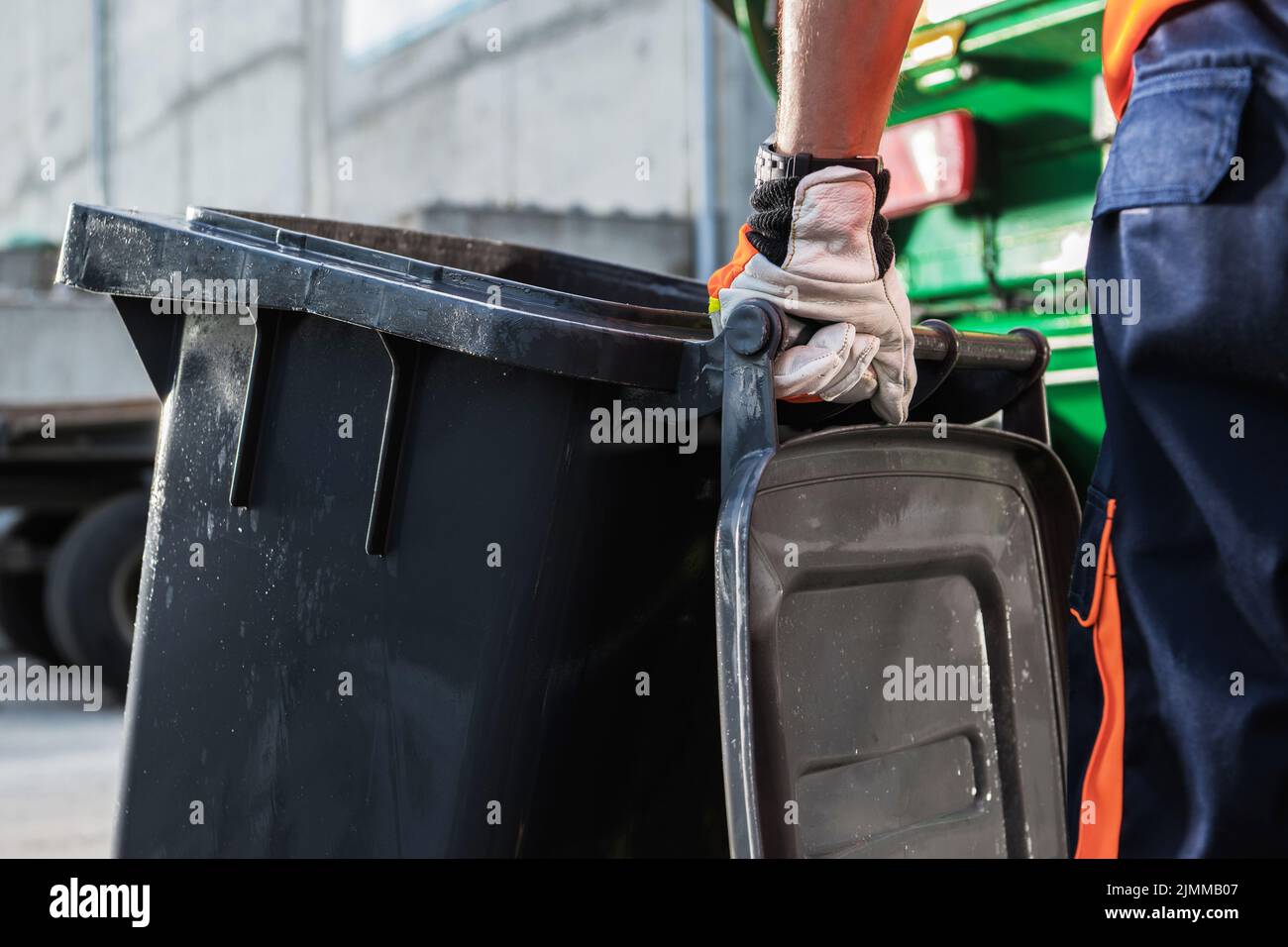 Garbage Truck Worker Moving Clean Black Trash Can Close Up. Waste Management Theme. Stock Photo