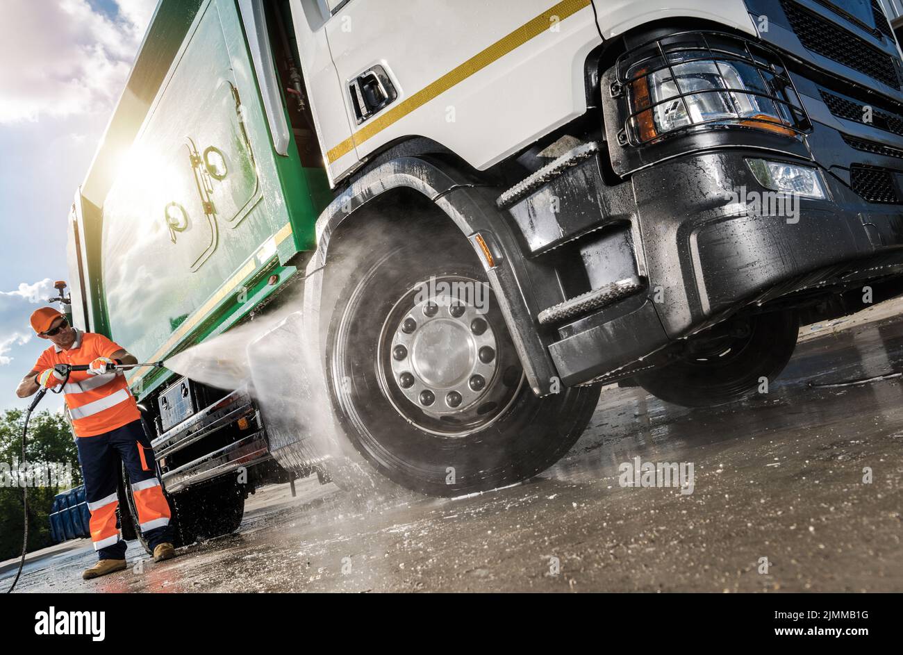 Heavy Equipment Washing Station Worker in His 40s Pressure Wash a Garbage Truck Stock Photo