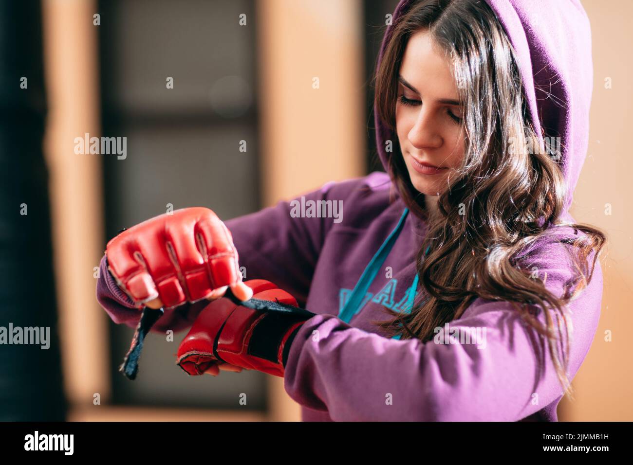 Smiling female athlete put on boxing gloves at gym Stock Photo Alamy