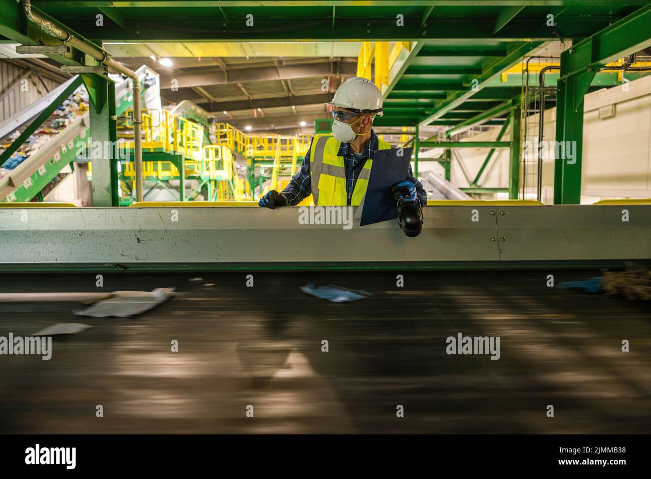 Recycling Plant Solid Waste Management Engineer Checking on Running Trash Material Conveyor. Making Documentation. Stock Photo