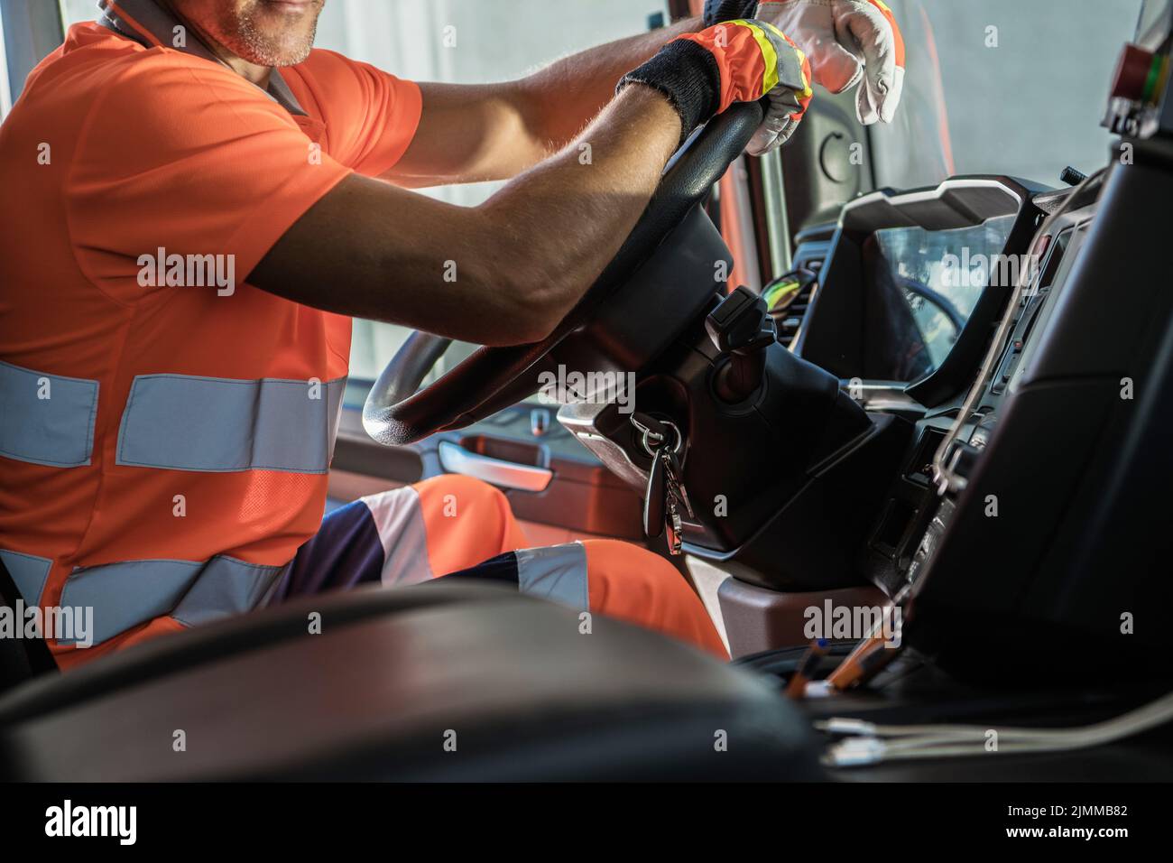 Heavy Duty Transportation Theme. Caucasian Semi Truck Driver Inside Vehicle Cabin Keeping His Hands on a Steering Wheel. Stock Photo