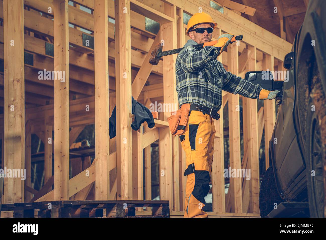 Caucasian Contractor Holding a Hammer on His Shoulder While Opening His Pickup Truck to Pack Up His Tools After Completing a Day's Work at the Constru Stock Photo