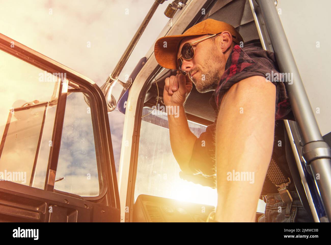 Closeup of Satisfied Truck Driver in Western Style Outfit Getting Out of His American Lorry After Successfully Completing a Delivery. Transportation I Stock Photo