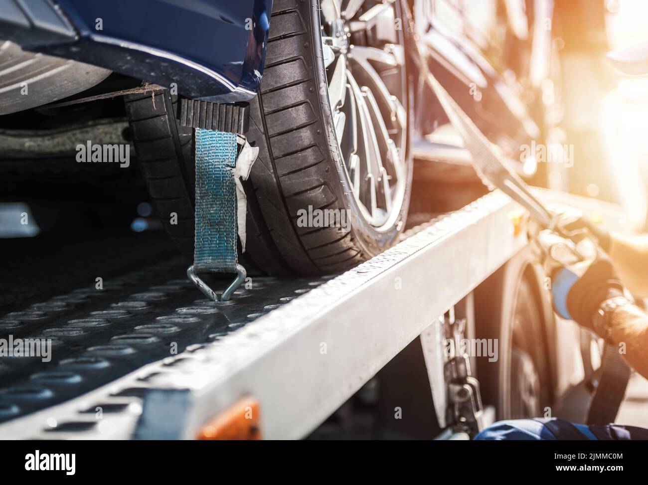 Closeup of Vehicle Wheel Secured on the Tow Truck with Tie Down Straps for Safe Transportation. Breakdown Assistance. Automotive Industry. Stock Photo