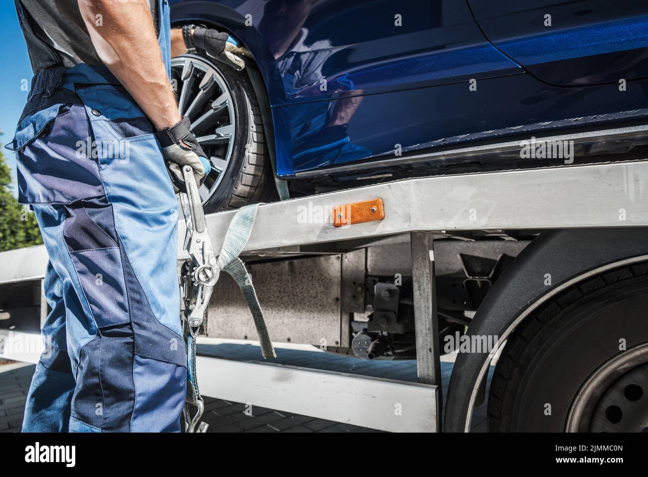 Male Worker Putting Transport Belts Around the Wheel of a Car on His