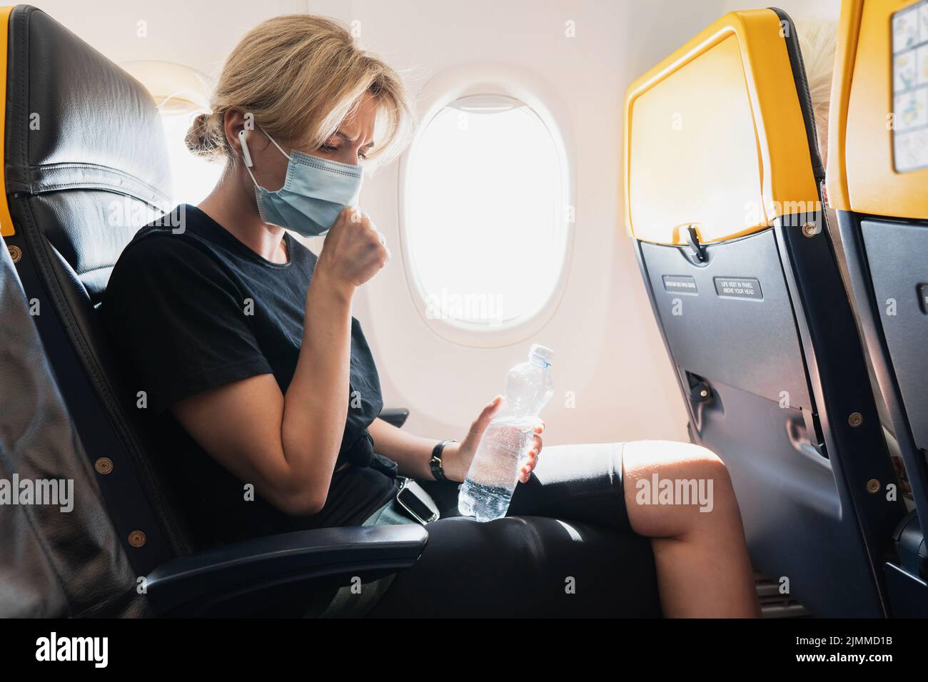 Woman wearing prevention mask during a flight inside an airplane Stock Photo