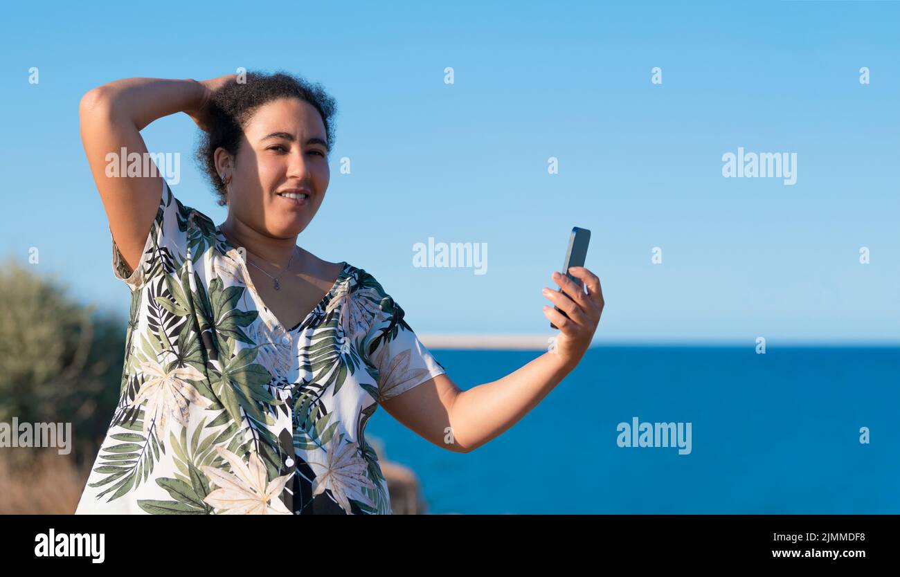 Pregnant woman taking a photo of herself near the sea Stock Photo