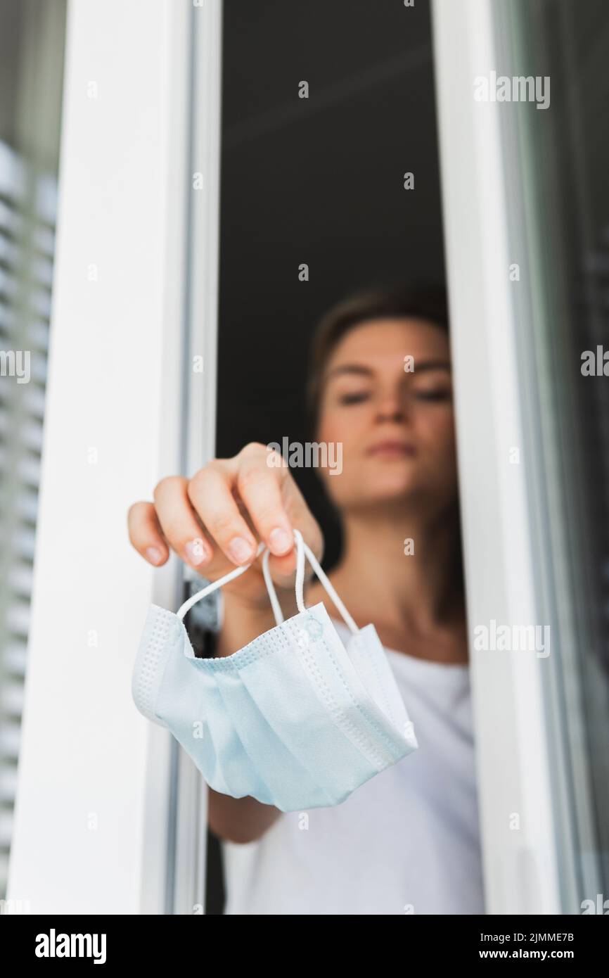 Woman throwing away used prevention mask. Symbol of pandemic ending