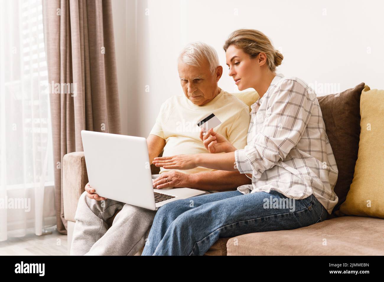 Woman explaining to elderly man how to use e-payment services Stock Photo
