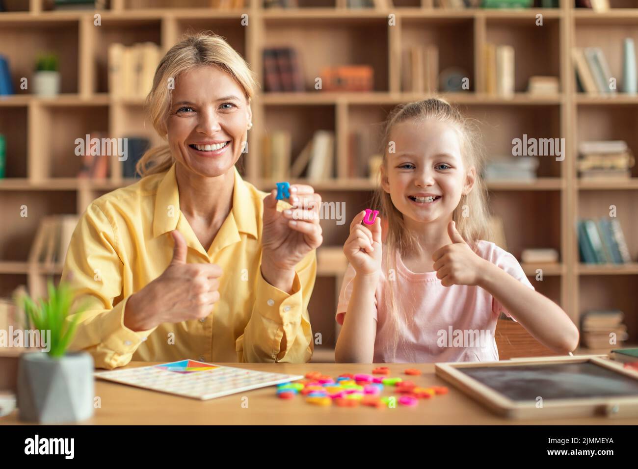 Professional speech therapist curing girl's problems and impediments, child learning letter R and U with private tutor Stock Photo
