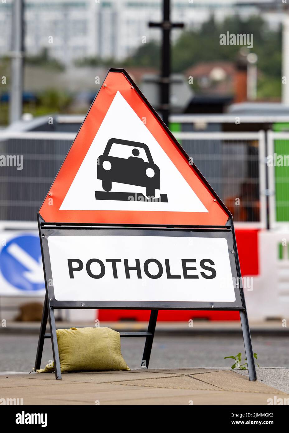 Potholes hazard warning sign dangerous road conditions. Red triangle