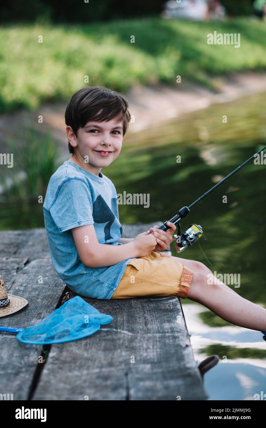 Smiling Teenage Boy Holding Catch Freshwater Fish In Hands Stock