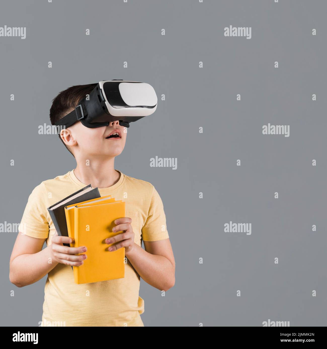 Boy using virtual reality headset while holding books Stock Photo