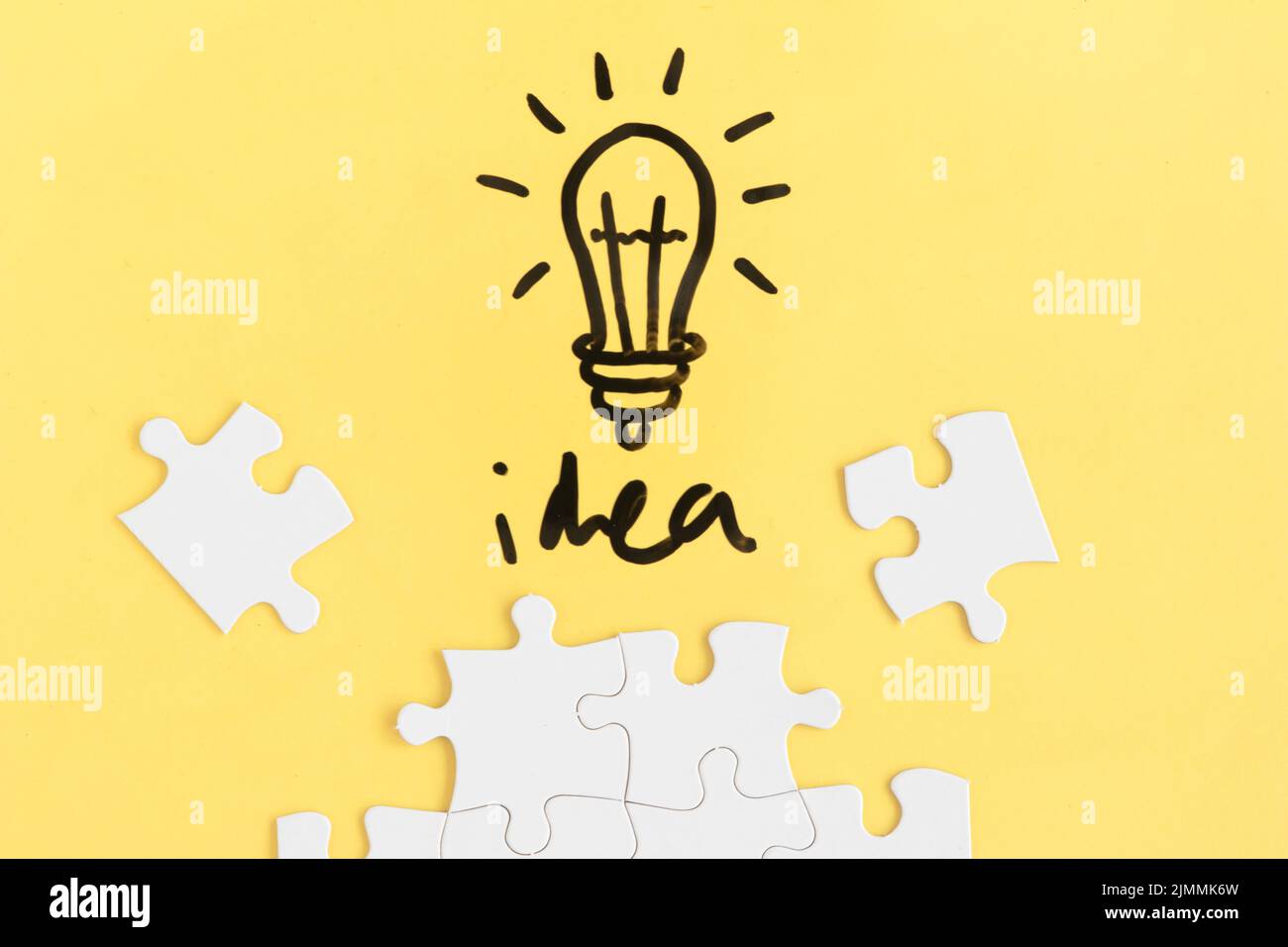 Jigsaw puzzle light bulb with idea word yellow background Stock Photo