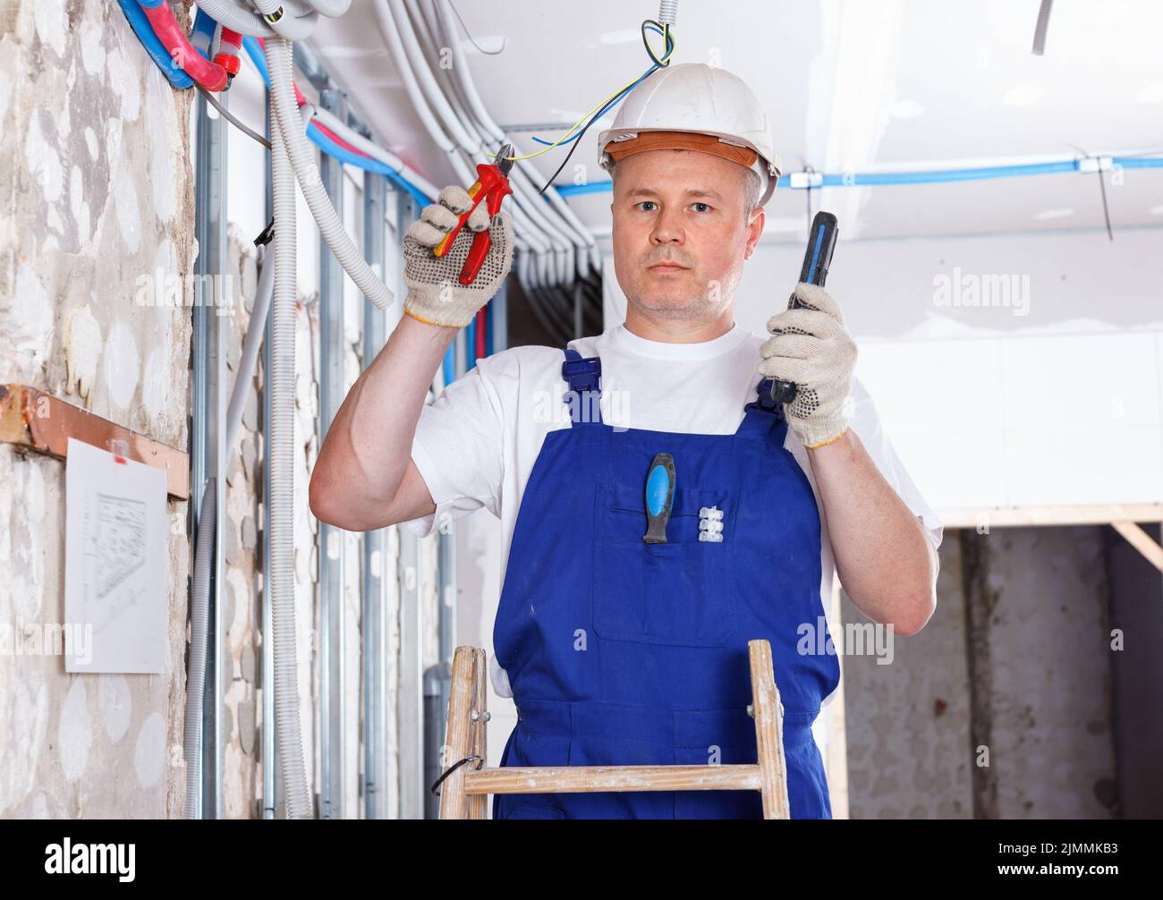 Experienced electrician laying electric wires in building under ...
