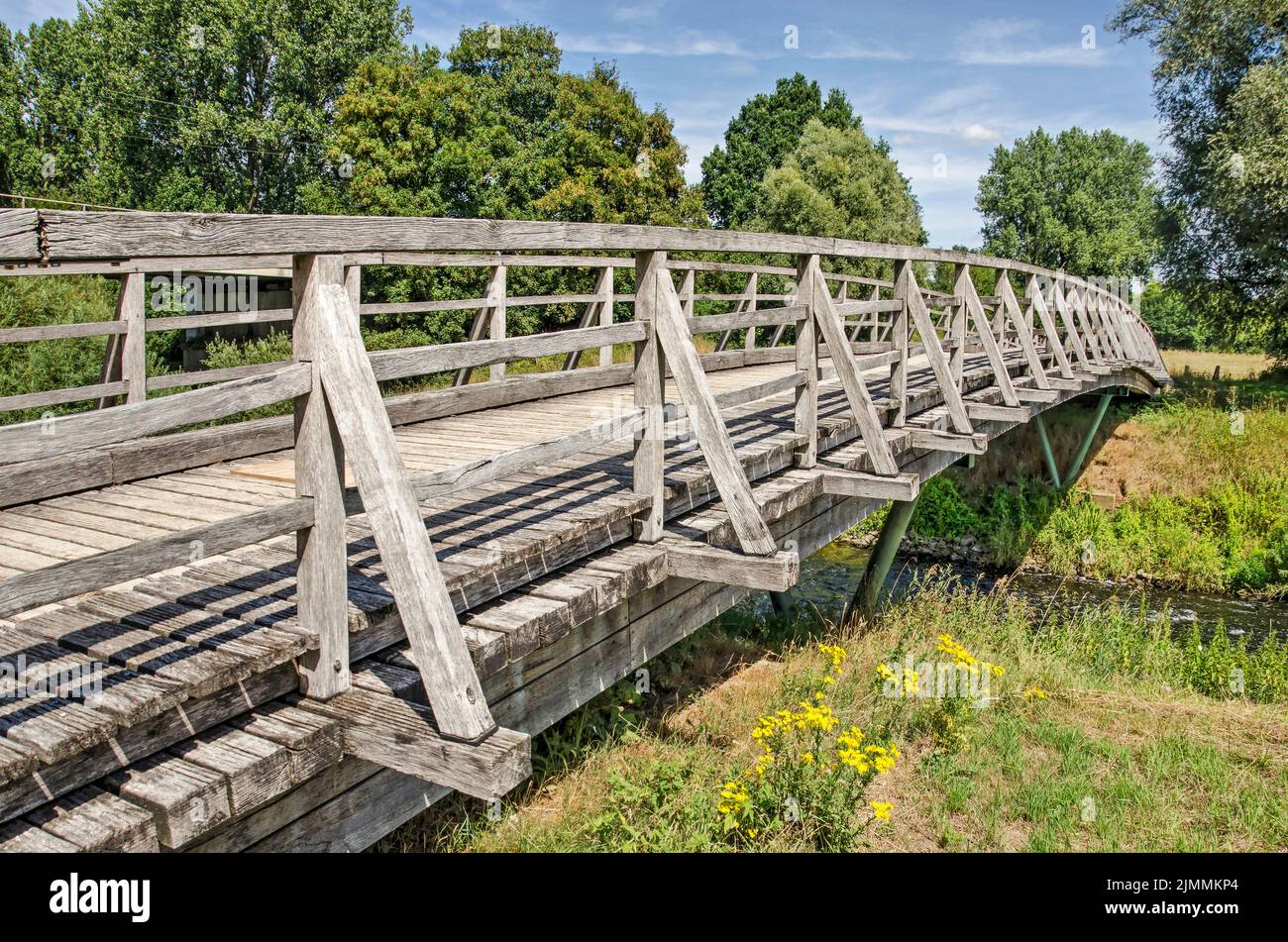 Munster, Germany, July 28, 2022: weathered wooden bridge across the river Ems in a green landscape on a sunny day in summer Stock Photo