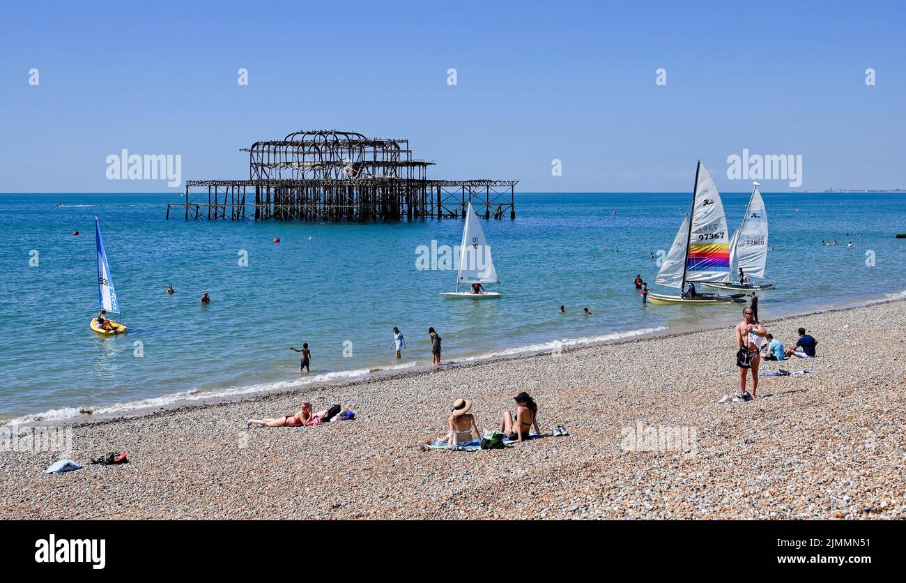 Brighton UK 7th August 2022 - Sunbathers enjoy the hot sunny weather on Brighton beach as thousands of visitors are in the city for the Pride Festival Weekend celebrations . More hot weather is forecast for parts of the UK over the next week with temperatures expected to go above 30 degrees again : Credit Simon Dack / Alamy Live News Stock Photo