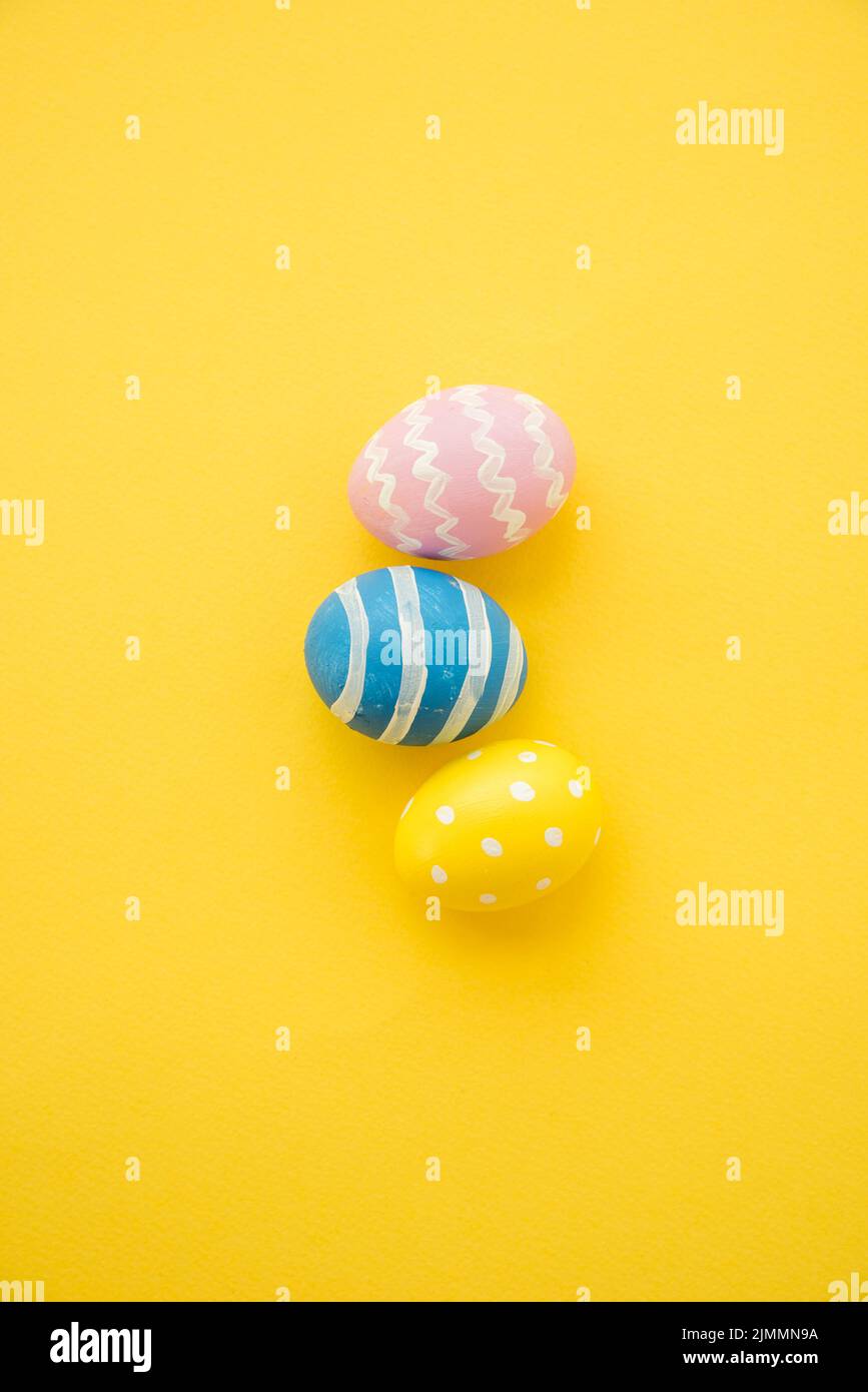 Three colourful easter eggs yellow table Stock Photo