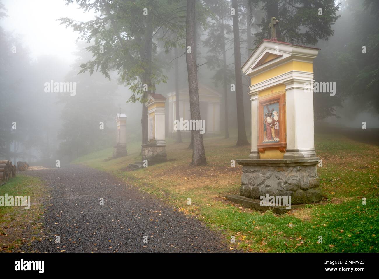 Chapels of a Way of the Cross at Mount Hostýn, a Catholic holy place in Moravia. A path leads into fog along the chapels. Stock Photo