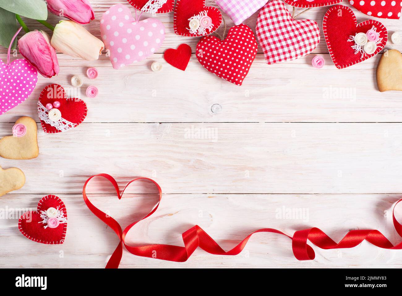 Sewed handmade fabric hearts tulips ribbon and cookies for valentine day on white wooden background with copy space Stock Photo