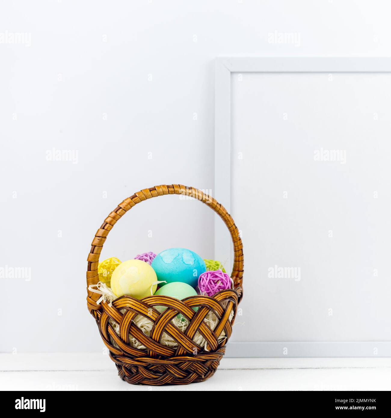 Basket with easter eggs near frame table Stock Photo