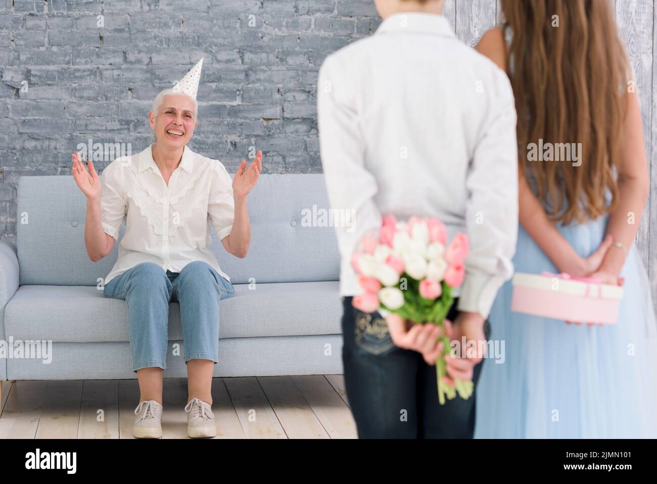 Children hiding gifts their back standing front their grand mother Stock Photo