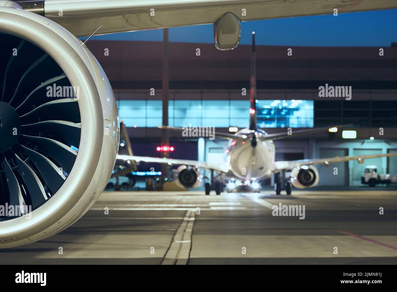 Close-up of jet engine of plane at busy airport. Preparation of airpane before night flight. Stock Photo