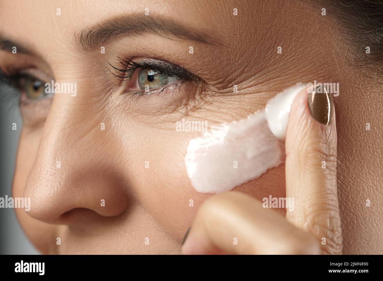 Middle aged woman applying anti-aging cream on her face Stock Photo