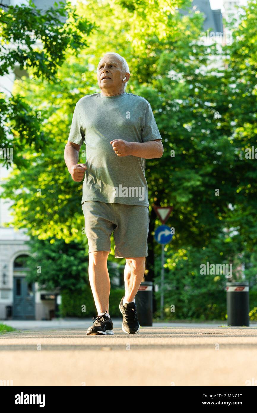 Elderly man during his jogging workout in a city park Stock Photo