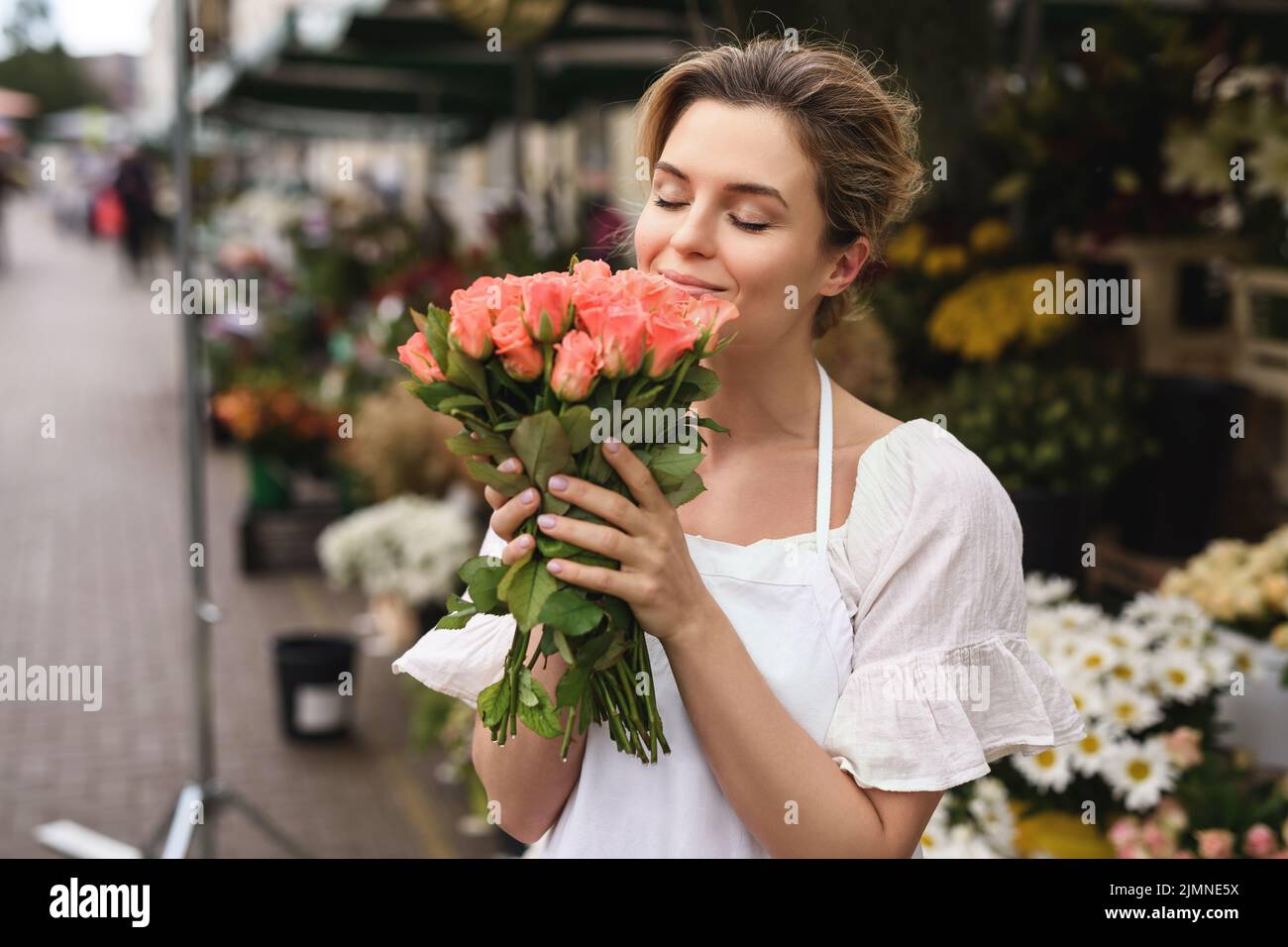 Woman florist with a heap of rose flowers in her little flower shop ...