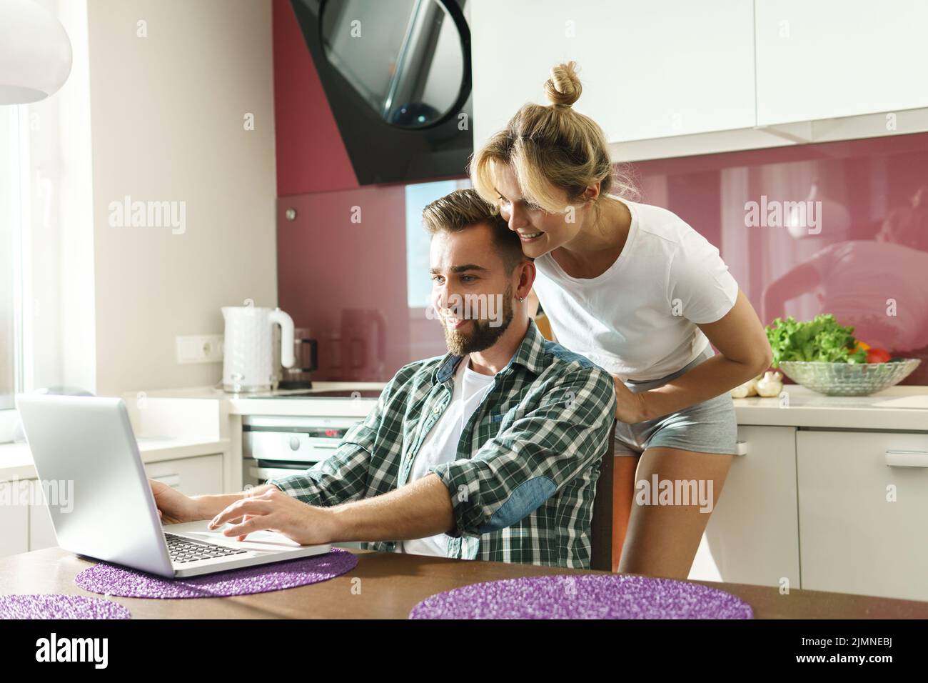 Happy couple using laptop in the kitchen at morning Stock Photo - Alamy