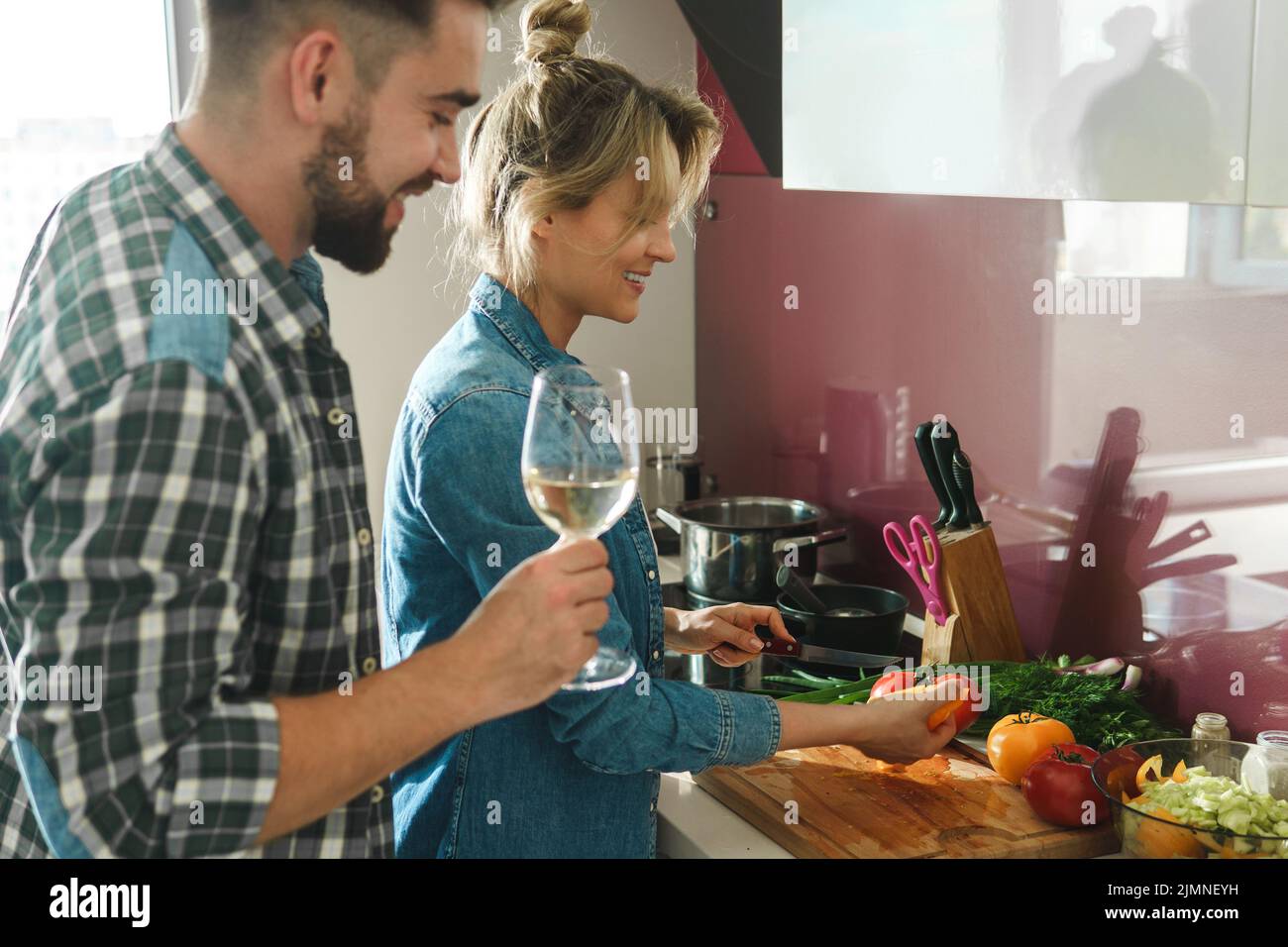 Happy couple cooking launch and drinking wine together in the kitchen