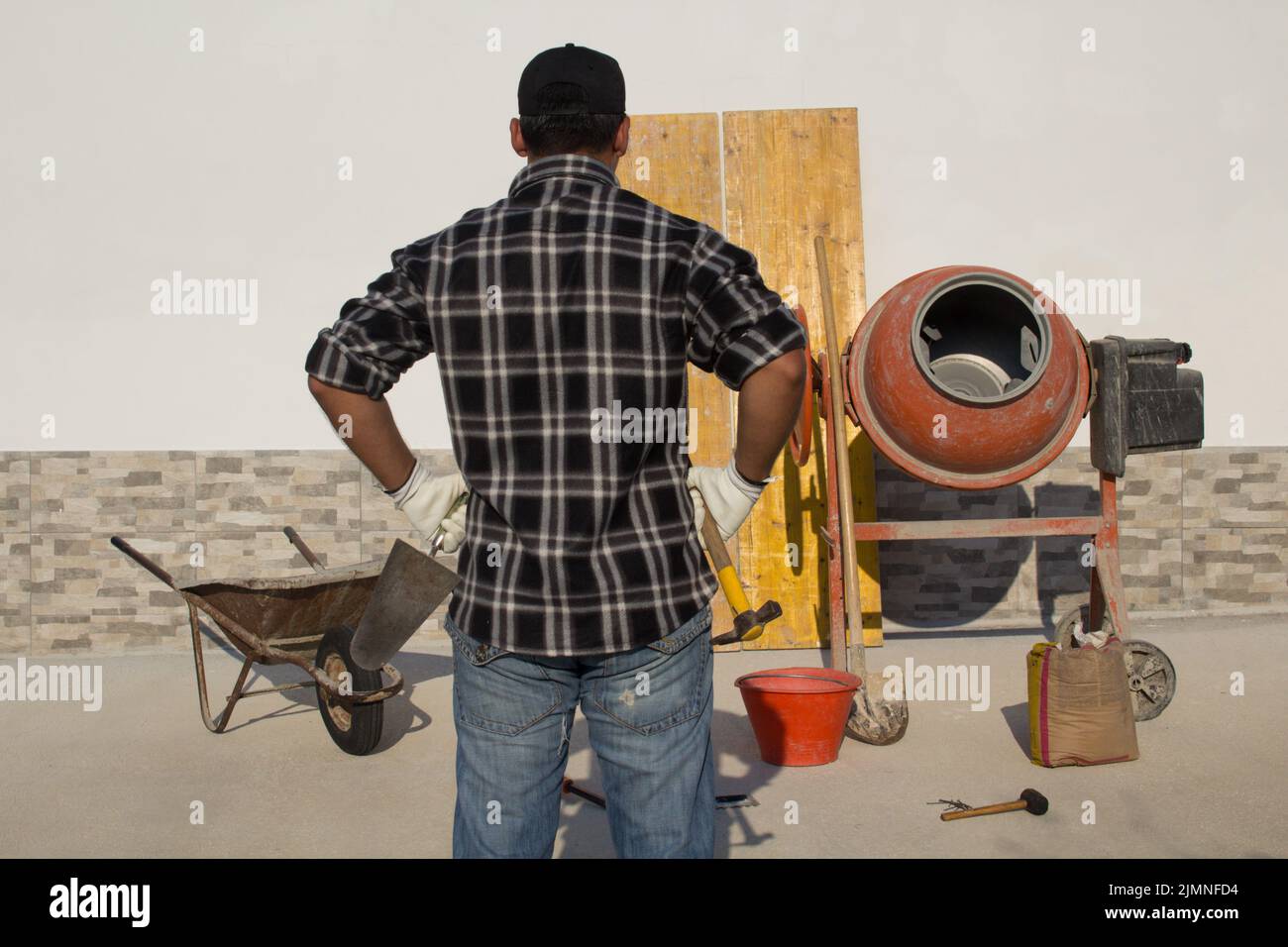 Back to back construction worker holding a hammer and trowel on a