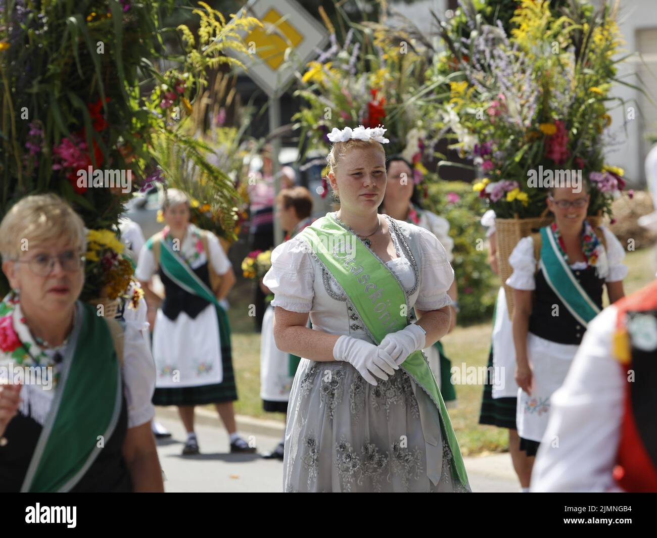 07 August 2022, Saxony-Anhalt, Hüttenrode: Kim Fischer, the new Grass Queen, walks through the village in the "Grasedanz" pageant. The Grasekönigin has been elected in Hüttenrode every year since 1885. The custom festival, which focuses on women, is celebrated annually on the first weekend in August. Photo: Matthias Bein/dpa Stock Photo