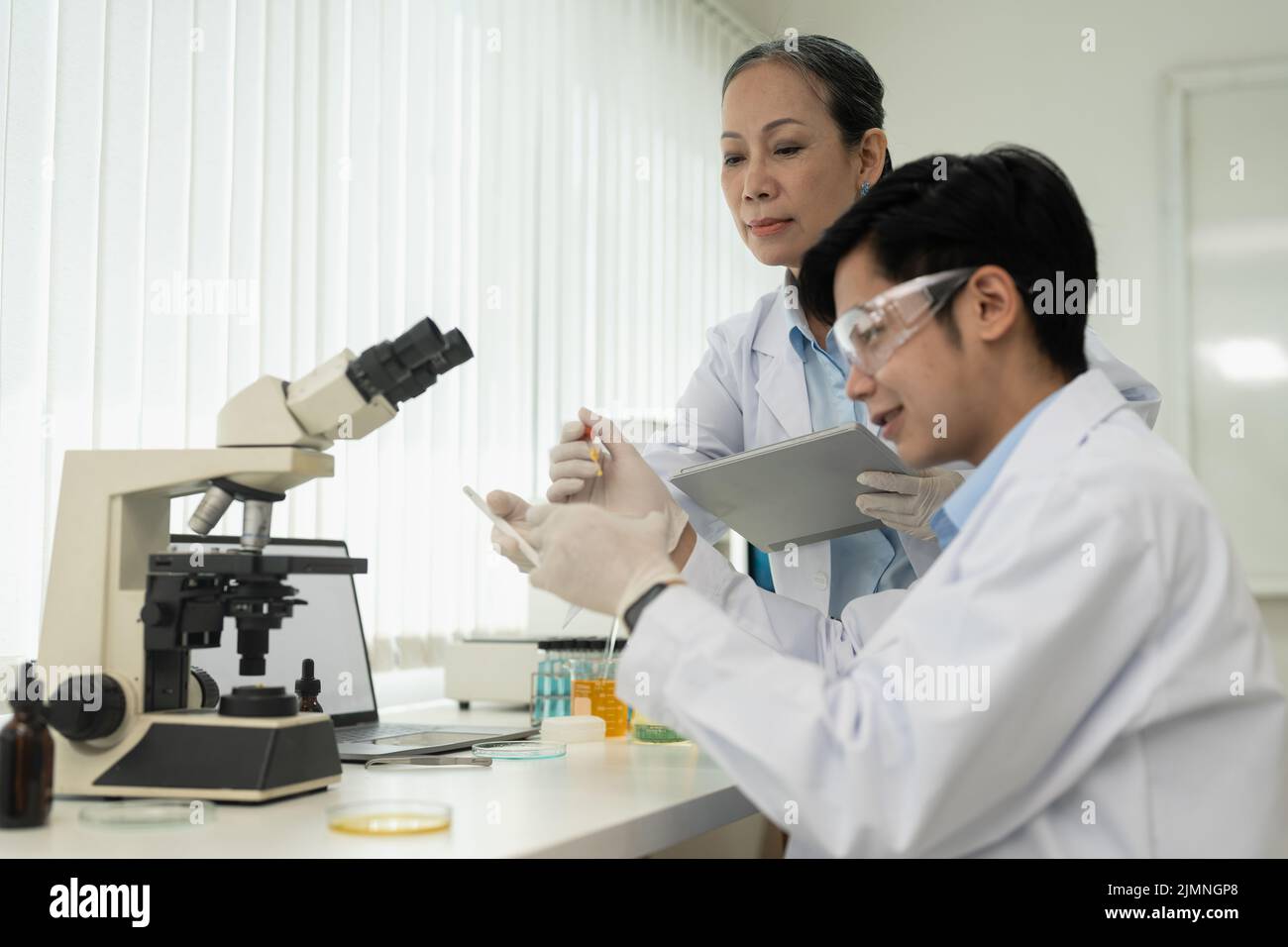 biochemical research scientist team working with microscope for vaccine ...