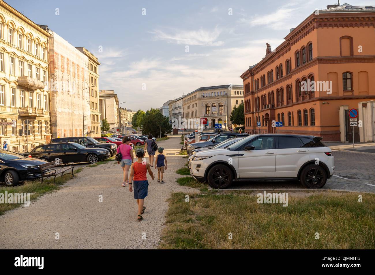 The women and kids walking from a parking place with cars to the Plac Wolnosci square Stock Photo