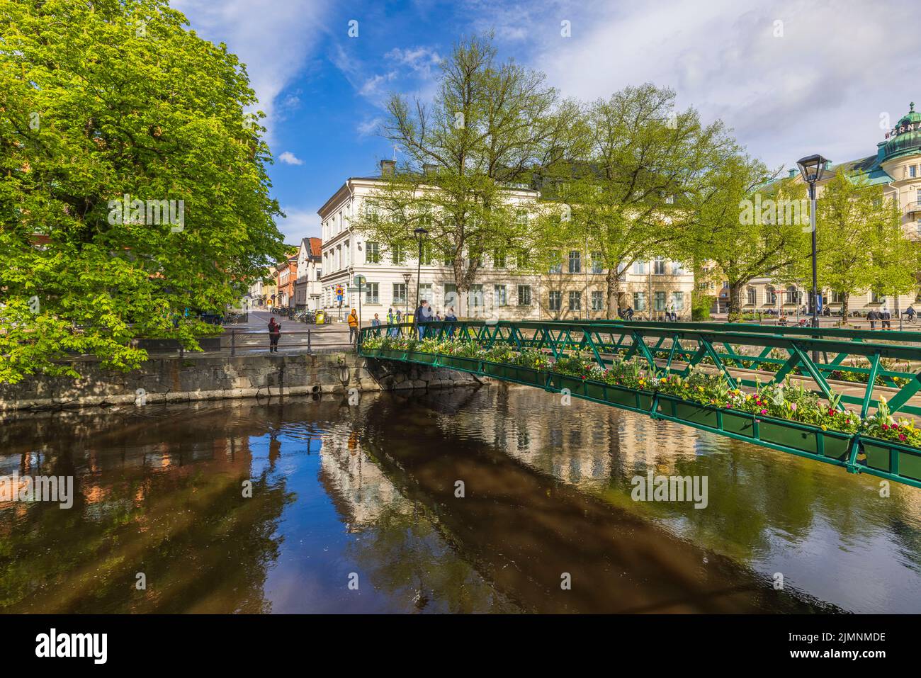 Beautiful calming cityscape view with bridge over small river decorated with flowers. Sweden. Uppsala. Stock Photo