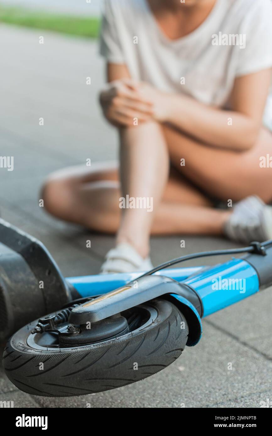 Young woman suffering from knee pain after e-scooter riding accident Stock Photo