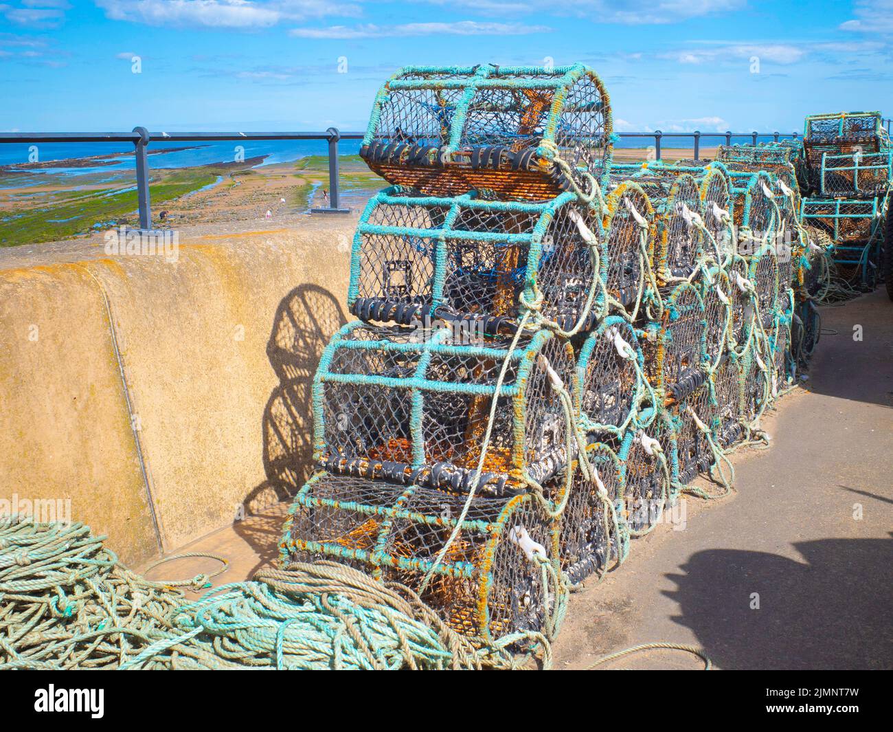Lobster or crab pots stacked on the Esplanade where fishing boats are parked in Redcar North Yorkshire UK Stock Photo