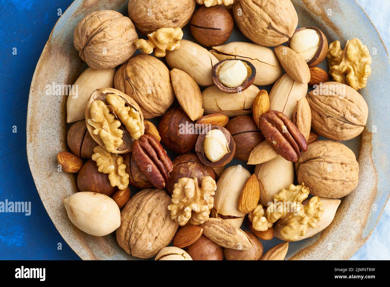 Classic blue in food. Mix of nuts on plate - walnut, almonds, pecans, macadamia Stock Photo