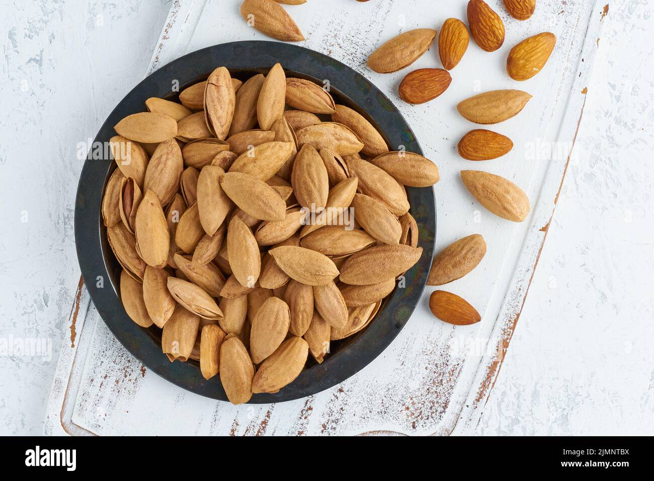 Top view plate with almonds in endocarp, bowl with drupe in shell on Stock Photo