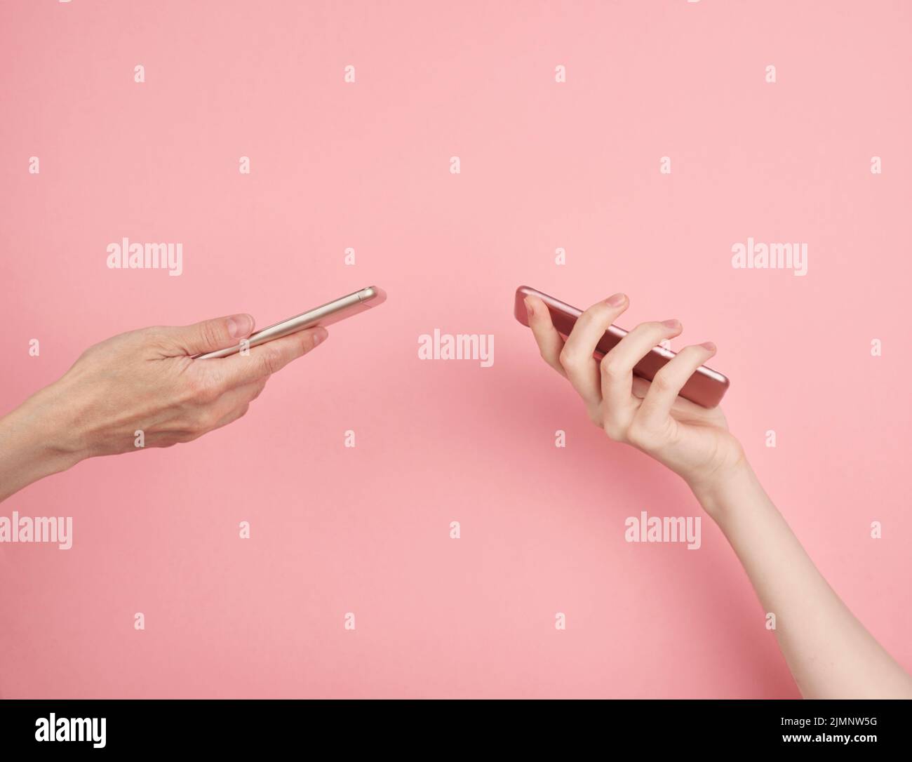 Two women hold phone on pastel pink background copy space side view Stock Photo