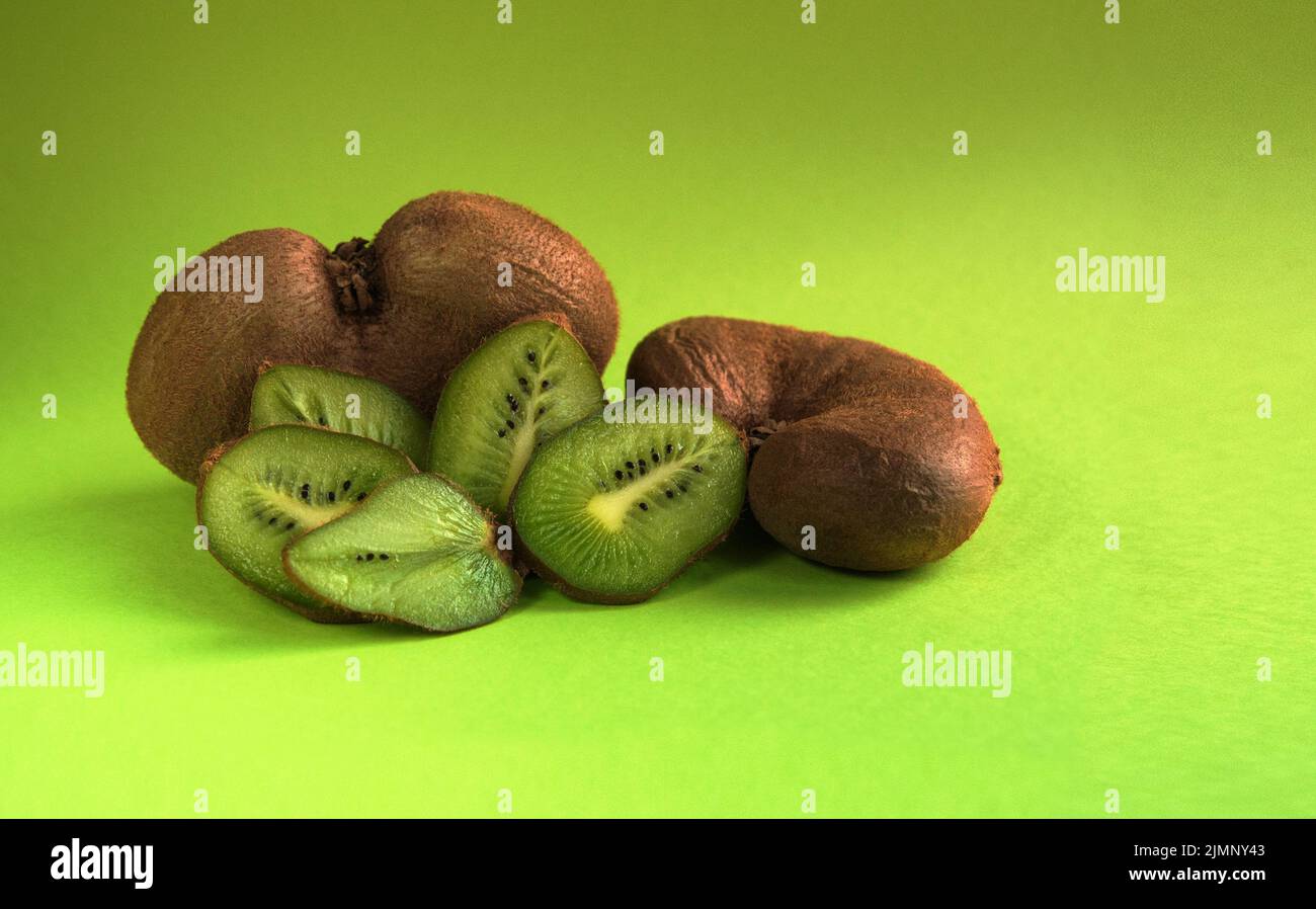 Ugly vegetable organic kiwi on a green background. Horizontal