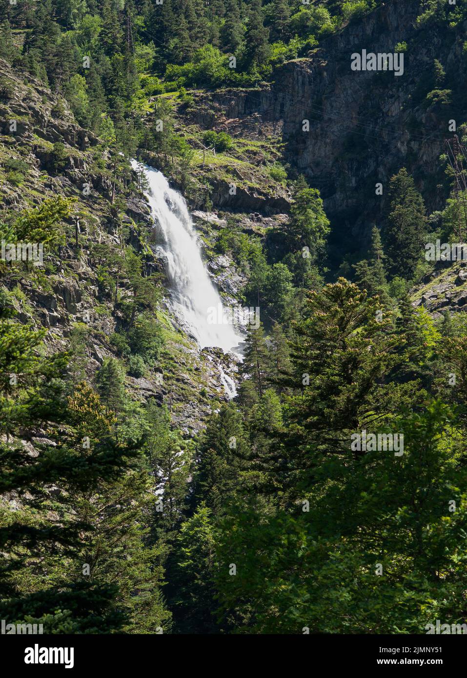 high mountain side waterfall amongst woodland and rock outcrops Stock Photo