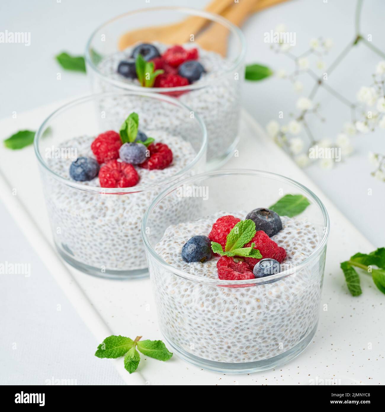Chia pudding with fresh berries raspberries, blueberries. Three glass, light background, side