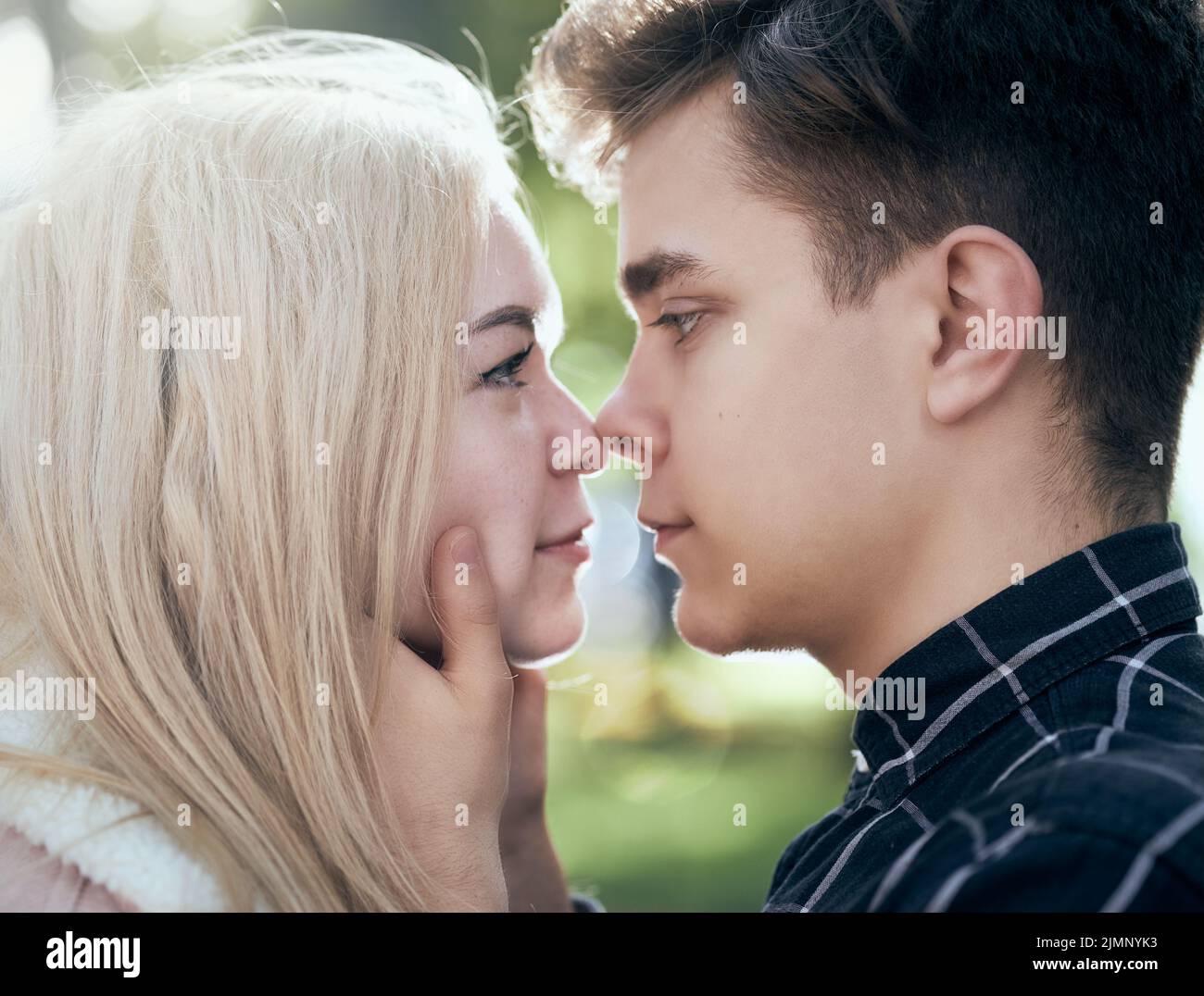 A man affectionately call looks at woman, guy and girl are worth close, touching the tips noses. Concept of teenage love and fir Stock Photo